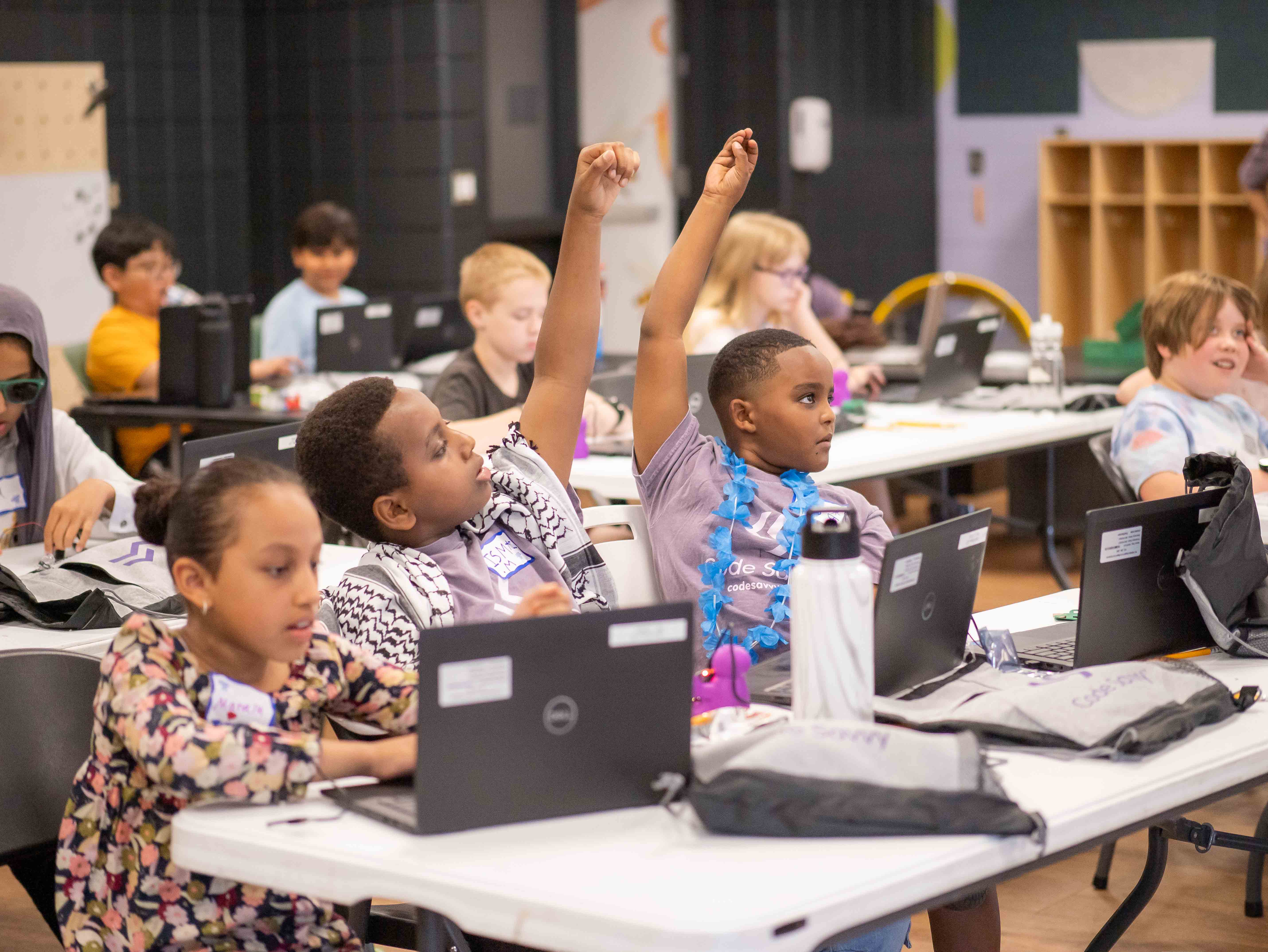 Students raising their hands during a Code Savvy hackathon